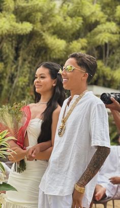 a man and woman standing next to each other in front of some people with cameras