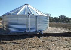 a large metal tank sitting on top of a dry grass field