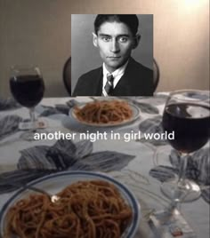 a table topped with two plates of spaghetti and a glass of wine next to it