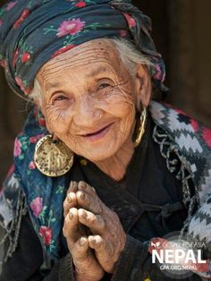 an old woman is smiling and holding her hand up to her face with the words nepal written on it