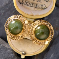 This vintage pair of paddle-back earrings each feature a round cabochon nephrite jade in a bezel setting.  The jade is accented with a lovely gold wire work frame.  The earring are crafted in 14k yellow gold and are for non-pierced ears. Vintage Green Cabochon Earrings, Vintage Jade Round Earrings, Vintage Hallmarked Green Earrings, Vintage Green Jade Earrings, Vintage Round Clip-on Earrings With Polished Finish, Antique Engagement Rings Sapphire, Estate Jewelry Rings, Wedding Ring Diamond Band, Jade Earrings