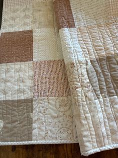 a close up of a quilt on a wooden floor with a white and brown blanket