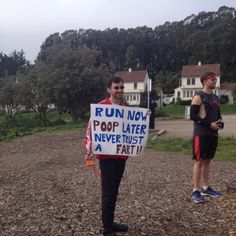 two men standing in the dirt holding up signs that read run now pop later never trust a fart