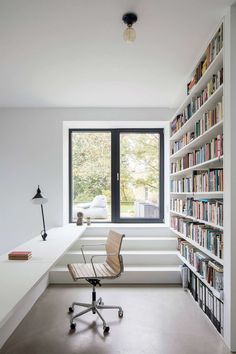 a chair sitting in front of a window next to a book shelf filled with books