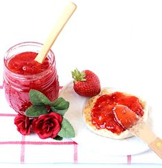 strawberry jam in a jar and fresh strawberries on a plate with a wooden spoon