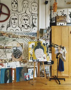 an artist's studio with various paintings on the wall