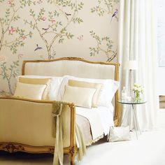 a white bed sitting next to a window with curtains on top of it and a bird painted on the wall