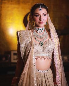 a woman in a bridal outfit with jewelry on her head and shoulders, posing for the camera