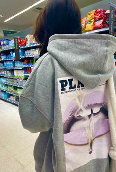 a woman wearing a hoodie with the word pla on it in front of a grocery store aisle