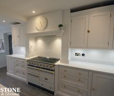 a kitchen with white cabinets and a clock on the wall above the stove top oven