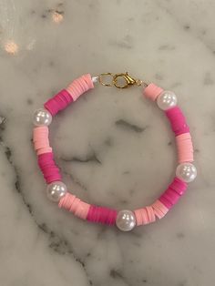 pink and white beaded bracelet on marble countertop with gold plated clasps