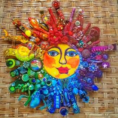 a sun face made out of glass beads on a wicker surface with other items around it