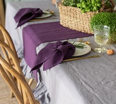 the table is set with purple linens and place settings