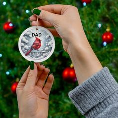 a person holding up a christmas ornament with a cardinal on it's side