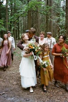 a group of people that are standing in the woods with one woman kissing another man