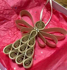 an ornament in the shape of a christmas tree is sitting on a red piece of paper