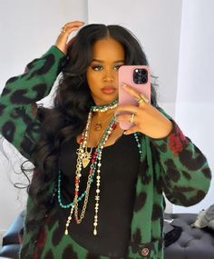 a woman taking a selfie in front of a mirror wearing a green and black top