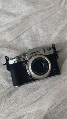 an old camera sitting on top of a white bed sheet with the word fujita written on it