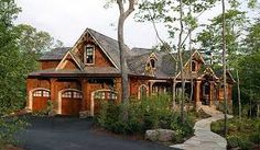 a house in the woods with lots of trees and bushes around it, along with a paved driveway