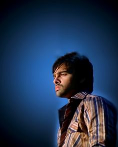 a man in striped shirt and tie looking off into the distance with blue sky behind him