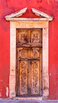 an old wooden door on the side of a red building with white trimmings