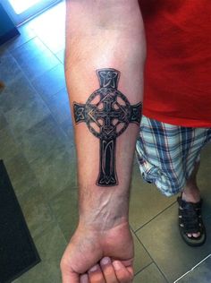 a man with a cross tattoo on his arm