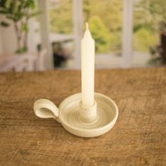 a white candle sitting on top of a wooden table