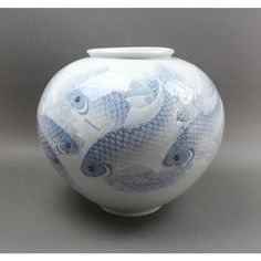 a white and blue vase with fish on it's side, sitting on a table