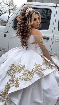 a woman in a white and gold wedding dress sitting on the back of a truck