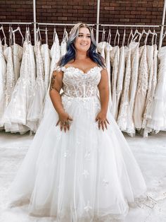 a woman standing in front of some wedding dresses