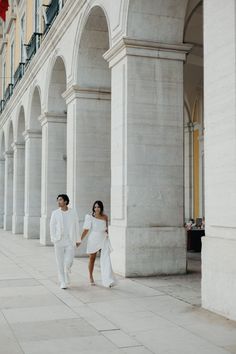 a man and woman in white are walking down the street holding hands with each other