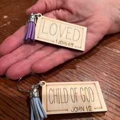 two keychains that say loved and child of god with tassels on them