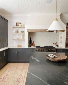 a kitchen with black counter tops and gray cabinets, along with a basket on the island