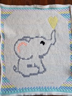 a crocheted blanket with an elephant holding a heart shaped balloon in the middle