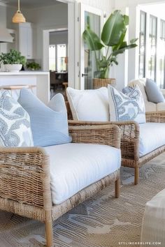 two wicker couches with blue and white pillows on them in a living room