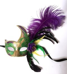 Stylish colorful masks with side flames up the left side. Masks have correlating glittered color accents across the face of the mask with matching feathers and plumes attached to the left side with a matching rose. Each mask with black ribbons for tying. Mardi Gras Masks And Prosthetics, Green Masquerade Mask For Mardi Gras, Mardi Gras Themed Event Masquerade Mask, Mardi Gras Eye Masquerade Mask For Themed Events, Mardi Gras Eye Mask For Themed Events, Adjustable Masquerade Mask For Mardi Gras, Green Masks For Mardi Gras Carnival, Feathered Masquerade Mask For Mardi Gras, Purple Masquerade Mask For Mardi Gras