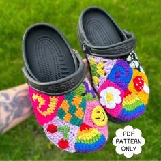 someone is holding up their colorful crocheted slippers in the grass with flowers on them