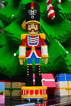 a lego nutcracker stands in front of a christmas tree