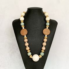 This dreamy boho necklace was hand beaded using a mix of warm neutral wooden beads (shades of light brown, rose gold, cappuccino, off white), 15mm round sea foam green ceramic beads, creamy white gemstones, and an amazing 30mm round white turquoise howlite focal bead gemstone (gorgeous highlights of lavender throughout).  The necklace measures approximately 25 inches in length and is secured with a silver toggle clasp.  The perfect accessory for the upcoming warmer months - natural and beachy! Necklace Wood, Wood Bead Necklace, Ethnic Necklaces, Wood Necklace, Summer Necklace, Turquoise Howlite, Necklace White, White Turquoise, Necklace Boho