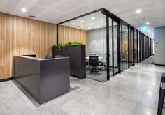 an empty office with glass walls and plants on the desks in front of it