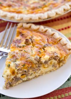 a slice of quiche on a white plate with a fork and another pie in the background