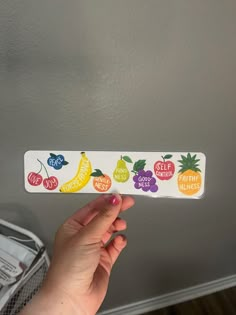 a person holding up a sticker with fruit on it