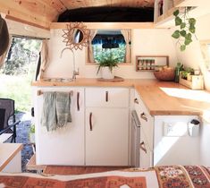 the interior of a tiny home with wood paneling and white cupboards, counter tops, and sink