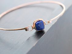 A simple, hammered 14K rose gold filled bangle features a gorgeous Lapis Lazuli faceted cube secured wtih 14k rose gold filled wire in my original bezel wrapped style for a modern and simple stacking bracelet. This bangle has a hinge style clasp to make it easy to put on take off and allows for a better fit. Bracelet - Choose your perfect fit. 7-7.5 inches in circumference is the most average size Lapis Lazuli Cube - approx 8 mm ** Photo #6 shows the same bracelets in Aquamarine & Pyrite wit Elegant Hammered Rose Gold Bracelets, Wire Wrapped Rose Gold Bracelet, Rose Gold Wire Wrapped Bracelet, Rose Gold Gemstone Bangle Jewelry, Elegant Rose Gold Hand Wrapped Jewelry, Elegant Hammered Rose Gold Jewelry, Minimalist Hand Wrapped Rose Gold Jewelry, Minimalist Hand-wrapped Rose Gold Jewelry, Adjustable Hammered Rose Gold Bangle