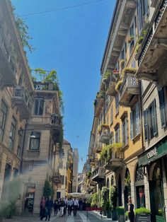 people are walking down the street in an old european city with tall buildings and balconies