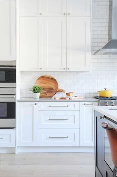 a kitchen with white cabinets and wooden cutting boards on the counter top, along with an oven