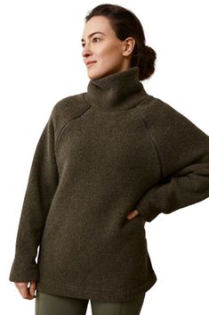 a woman in green pants and a brown sweater is standing with her hands on her hips