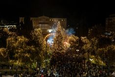 a large group of people gathered around a christmas tree in the middle of a park