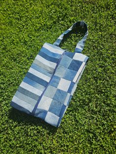 a blue and white tote bag laying on top of green grass in the sun