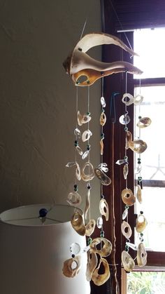 a wind chime with shells hanging from it's side in front of a window